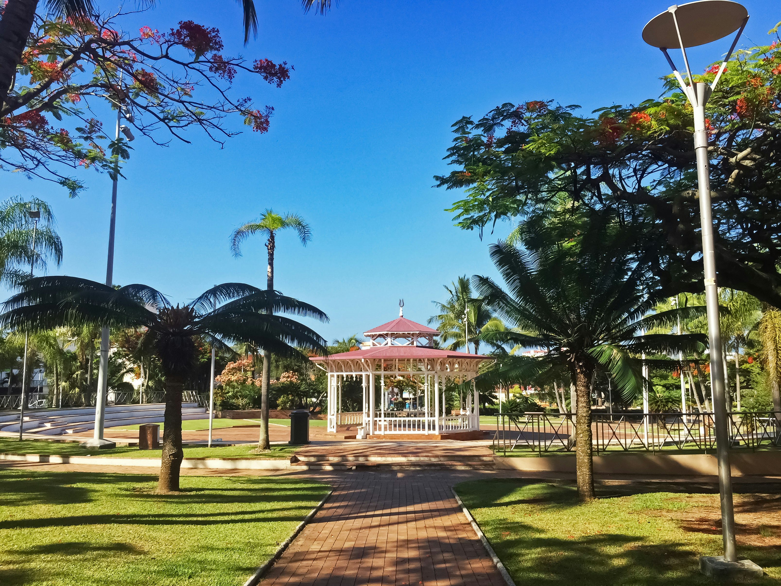 green trees and brown and white gazebo under blue sky during daytime